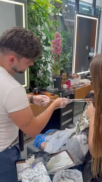 Profissional aplicando mechas com papel alumínio